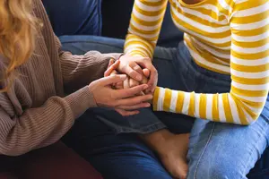 Women Holding Hands While Sitting on a Couch
